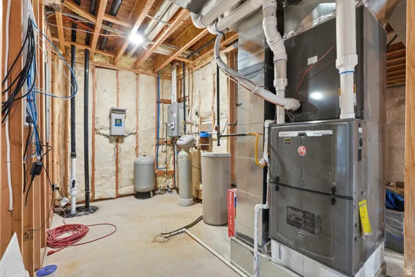 Utility room featuring a furnace unit, water heater, water softener, and exposed wooden framing