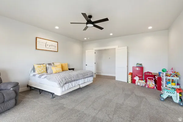 Spacious room featuring neutral carpeting, a modern black ceiling fan, recessed lighting, and white bi-fold closet doors