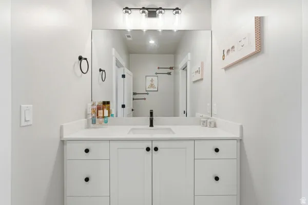 Bathroom vanity featuring a white countertop with integrated sink, white cabinetry, and matte black hardware
