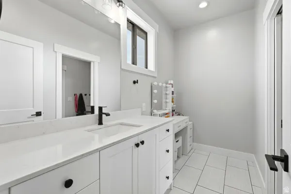Bathroom featuring a white vanity with integrated sink, a large mirror, and matte black fixtures