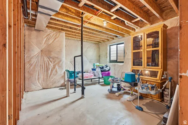 Unfinished basement with exposed ceiling joists and rough-in plumbing