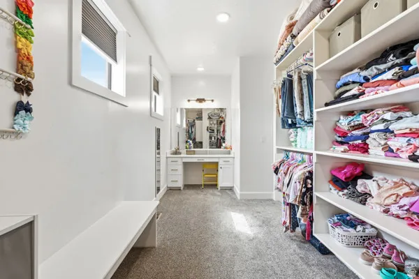 Spacious closet featuring extensive built-in shelving, hanging rods, and a dedicated vanity area with a mirror