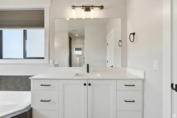 Bathroom vanity featuring a single undermount sink, white cabinetry, and a light-colored countertop