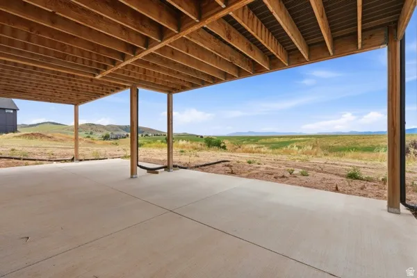 Covered concrete patio with wooden beam supports and an exposed joist ceiling