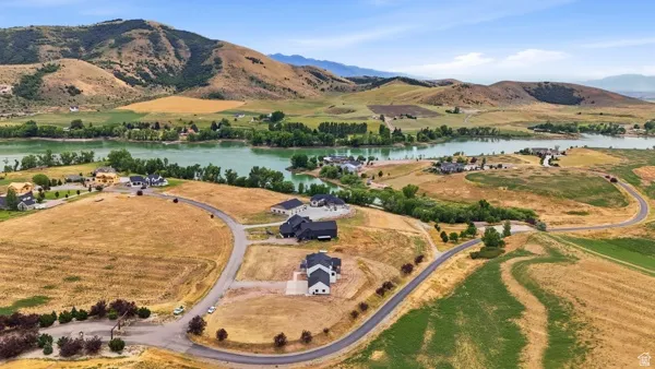Expansive land parcels featuring paved roads and established homes, situated with water frontage and mountainous backdrops