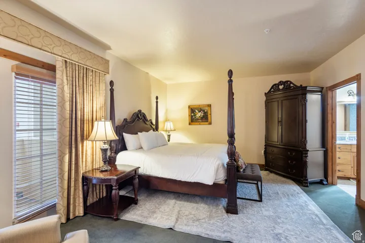 Spacious room featuring broadloom carpeting, a window with blinds and drapery, and a classic four-poster bed frame