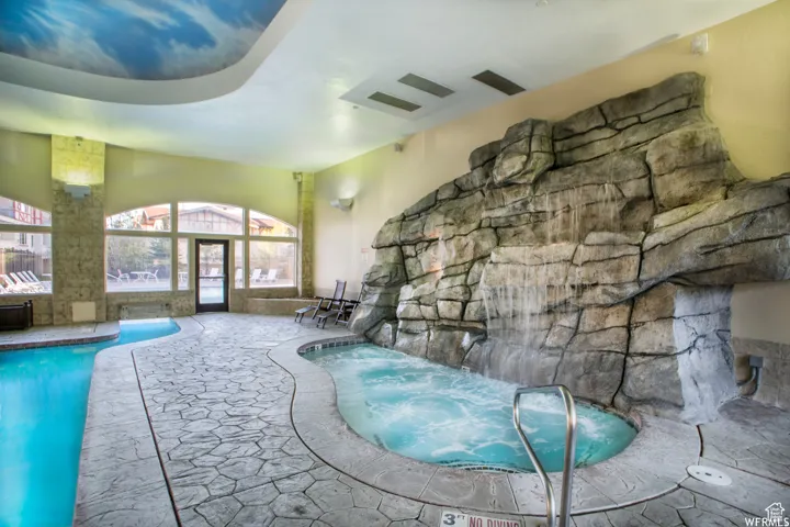Indoor aquatic area featuring a large rock-face waterfall and an integrated spa