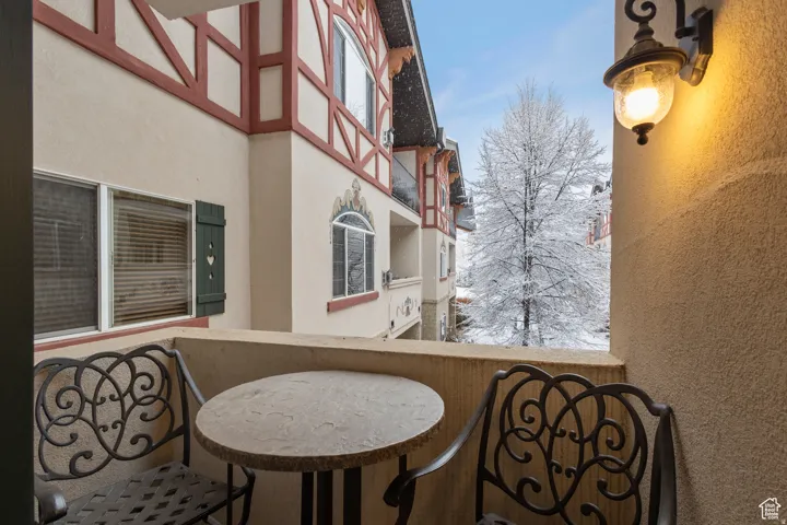 Private balcony featuring stucco exterior, decorative wall-mounted lighting, and balcony railing