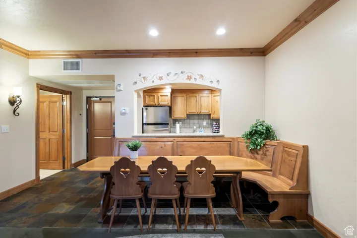 Kitchenette with wood cabinetry, stainless steel refrigerator, and tiled backsplash