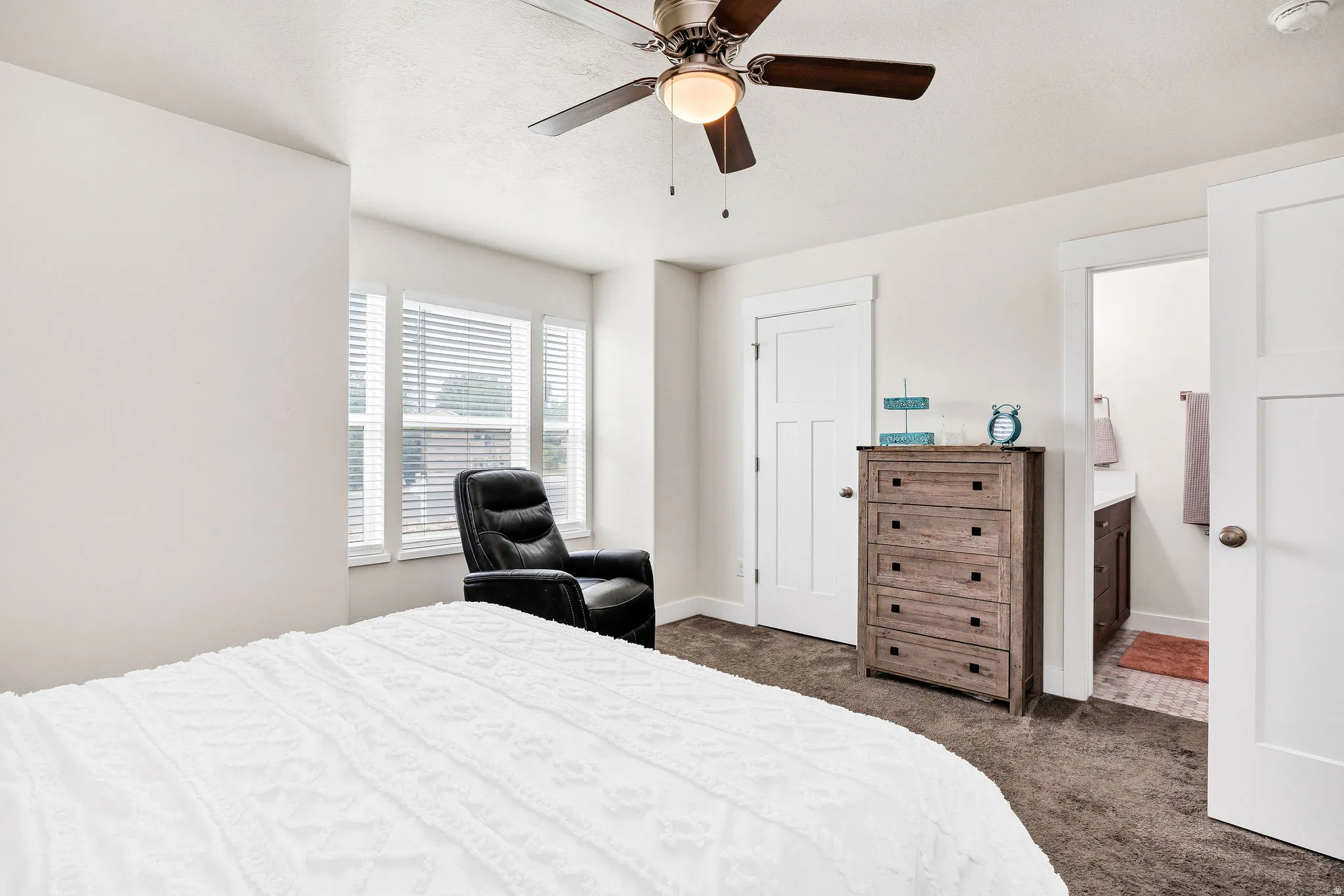 Carpeted room with a ceiling fan, white trim, and a three-pane window with blinds