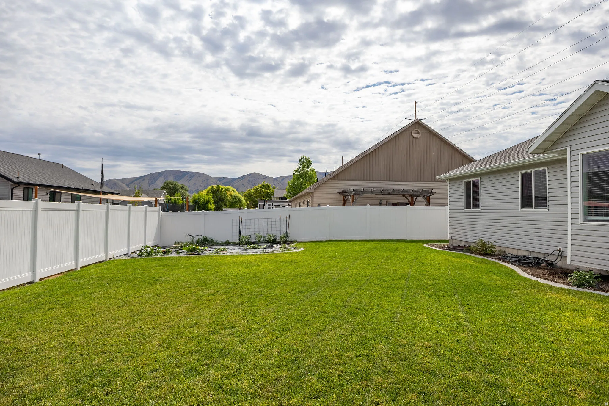 Expansive green lawn framed by a white privacy fence