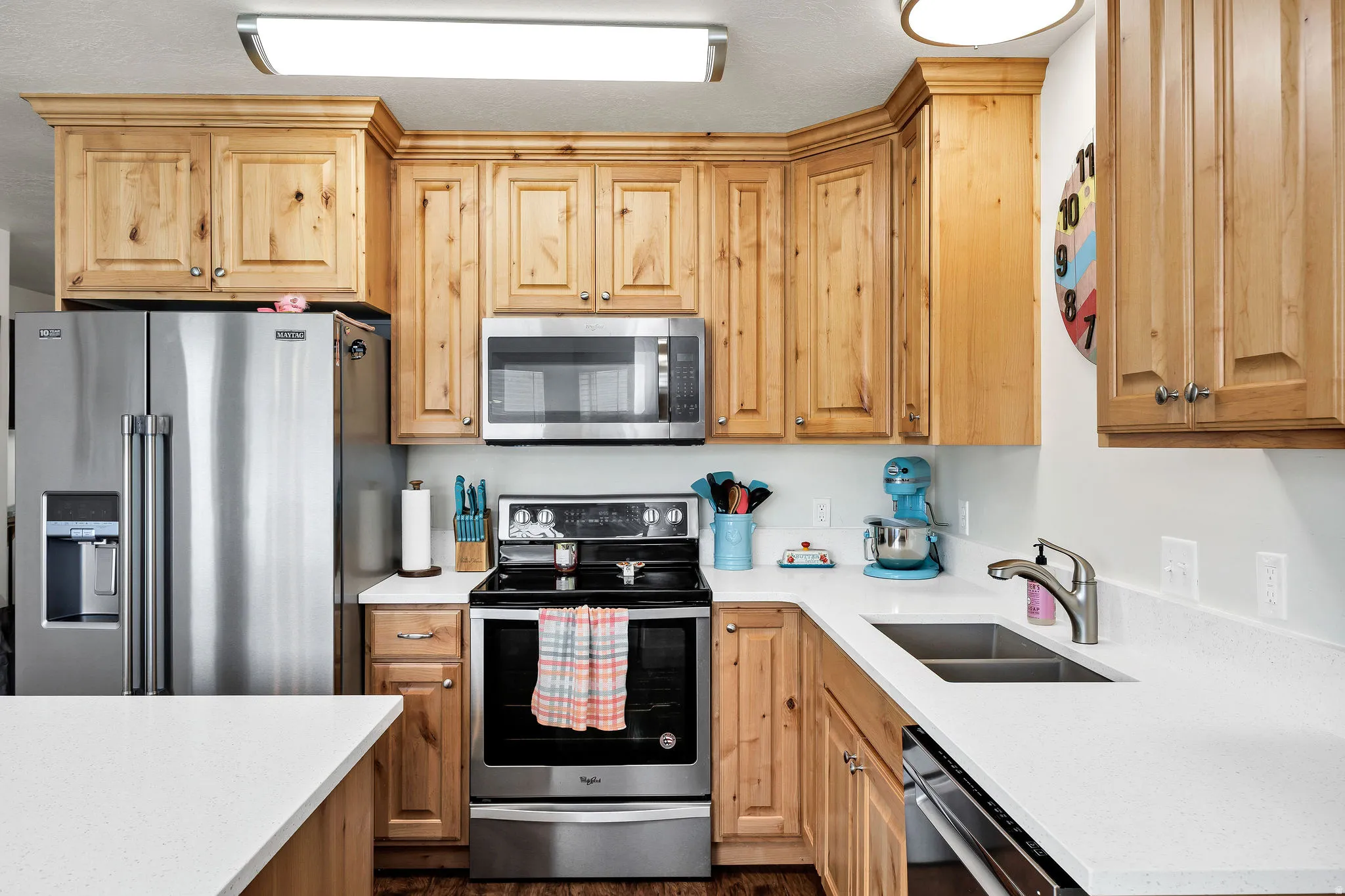 Kitchen featuring wood cabinetry, stainless steel appliances, white countertops, and a double basin sink