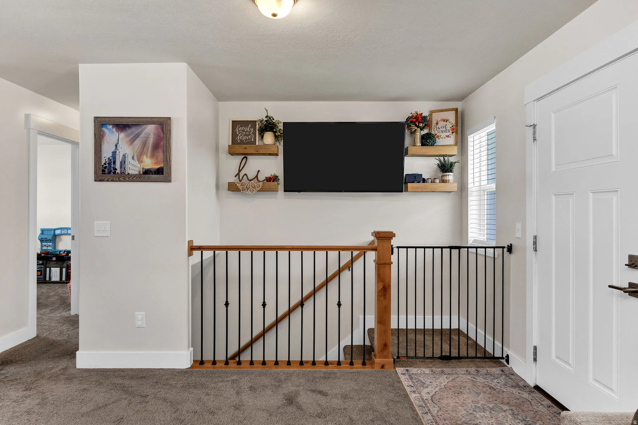 Staircase featuring wood handrails, black metal balusters, and a matching newel post