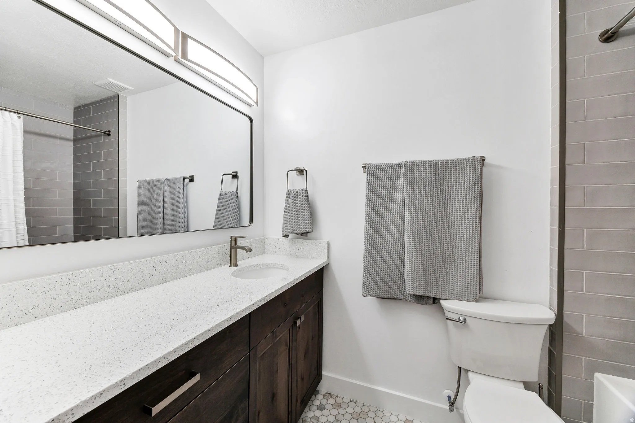 Bathroom featuring a vanity with dark wood-finish cabinetry, white speckled countertop, and an undermount sink