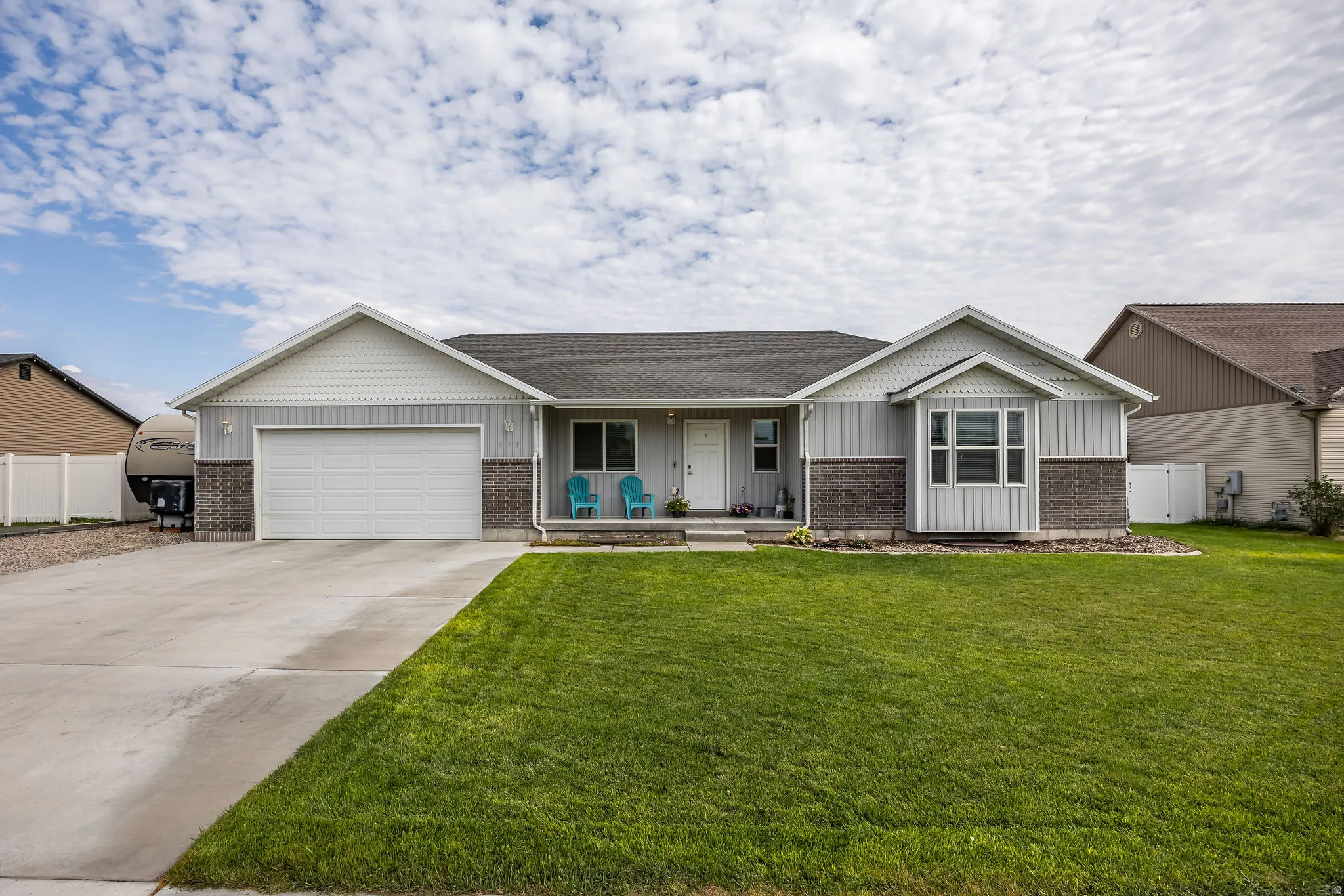 Single-story residence featuring light gray siding, dark brick accents, and a prominent front-facing garage