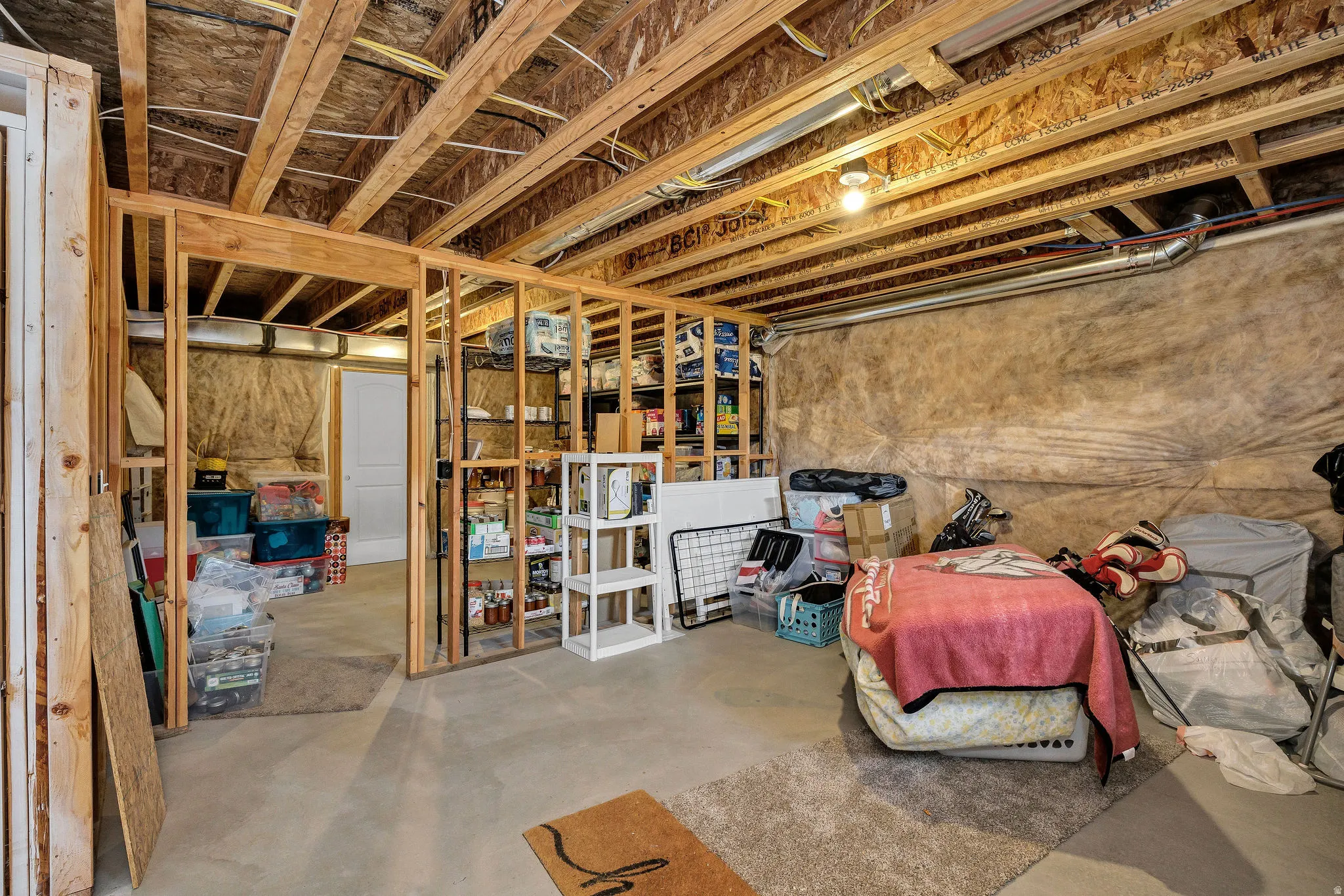Unfinished basement featuring exposed wood framing, concrete flooring, and exposed ceiling joists