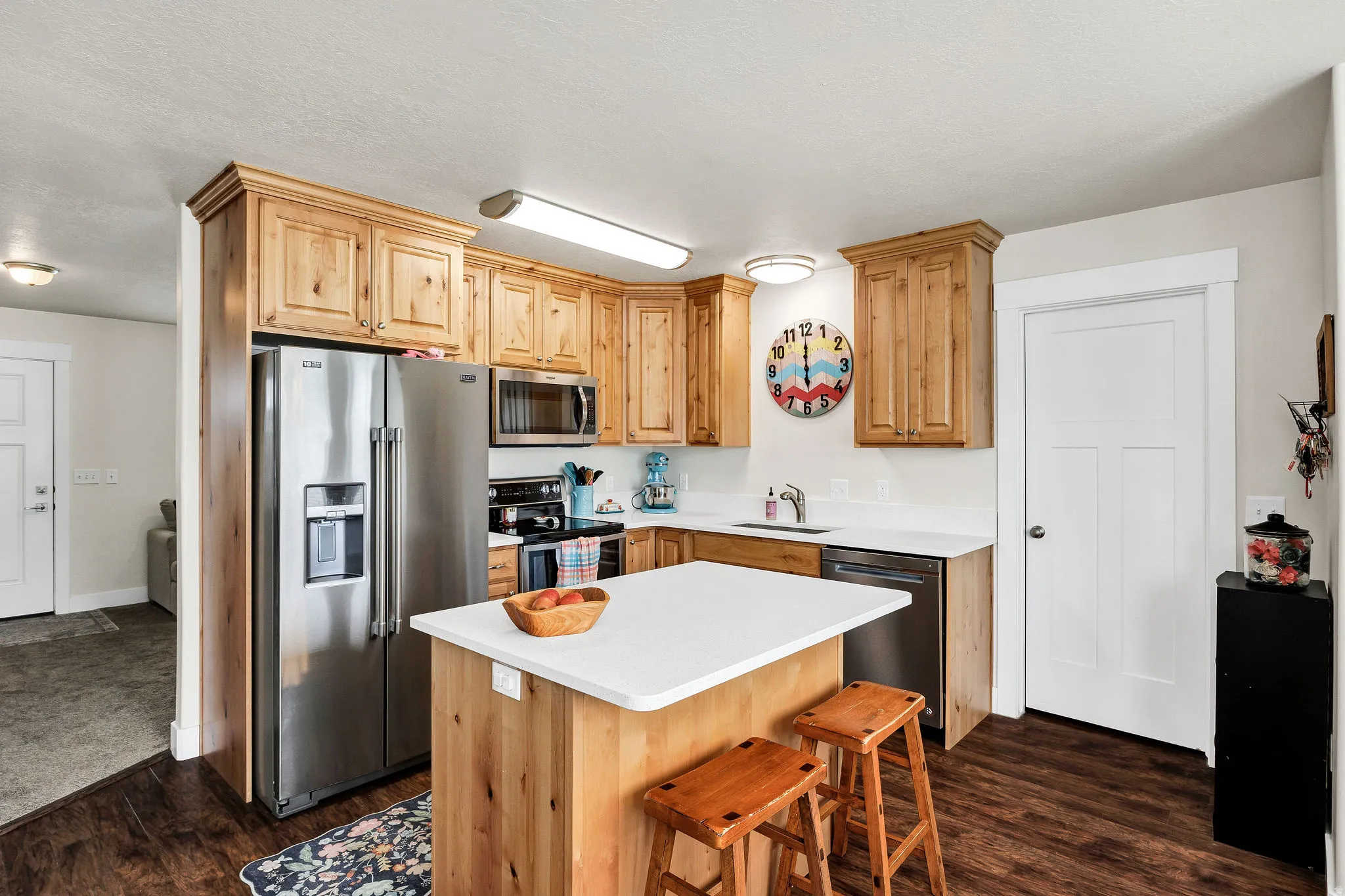 Kitchen featuring wood-finish flooring, light wood cabinetry, stainless steel appliances, a center island with a light-toned countertop, and recessed lighting