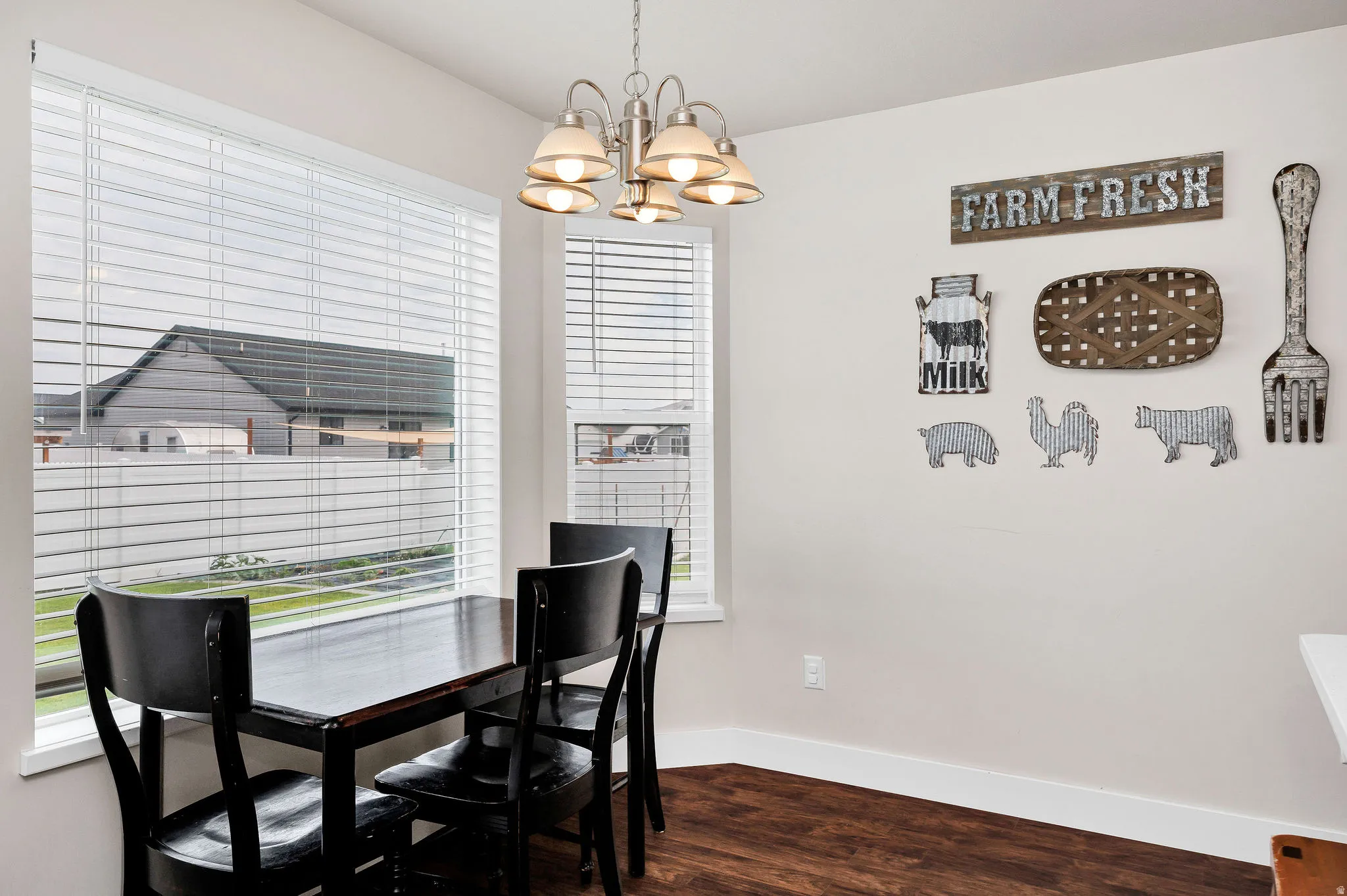Dining area featuring abundant natural light from two windows, wood-finish flooring, and a modern brushed nickel chandelier with frosted glass shades