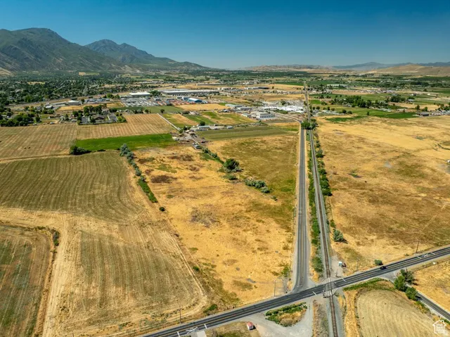 Expansive agricultural land featuring a railway crossing and distant mountain ranges