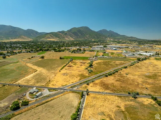 Expansive rural landscape featuring fields, paved roads, and distant mountains
