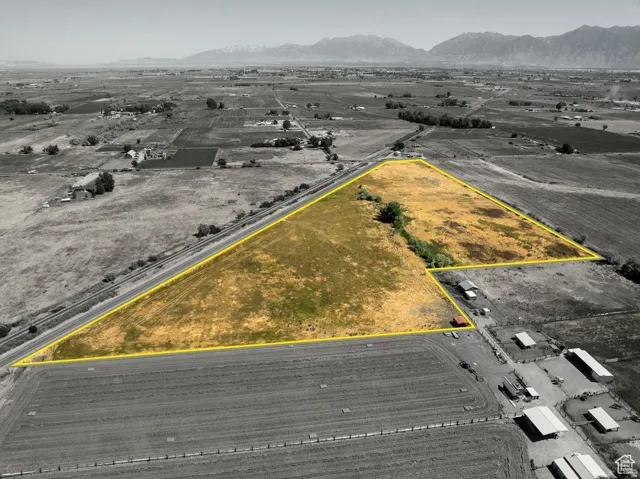 Expansive agricultural land featuring a natural water channel and mountainous terrain in the distance