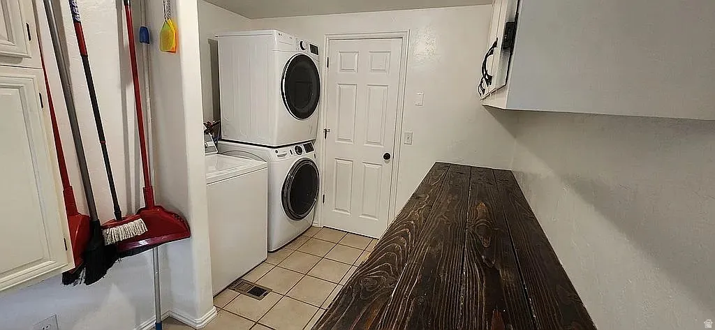 Laundry area featuring a dark wood-finish countertop, white cabinetry, and tile flooring
