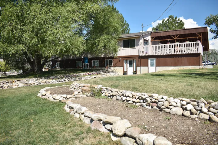 Two-story residence featuring a covered upper deck with white railing, and a ground-level patio door