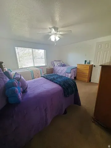 Spacious room featuring a ceiling fan with integrated lighting, a large window with blinds, and neutral wall tones