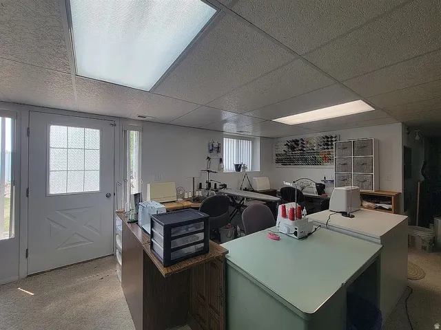 Spacious workroom featuring recessed fluorescent lighting, drop ceiling, and a white paneled door with frosted glass