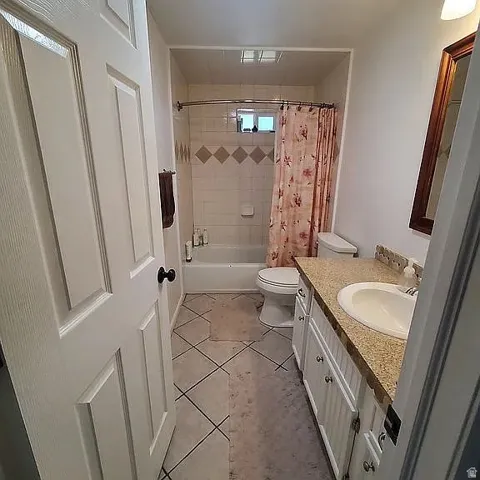 Bathroom featuring a tiled shower surround with accent band, a white bathtub, and a vanity with a light-colored countertop