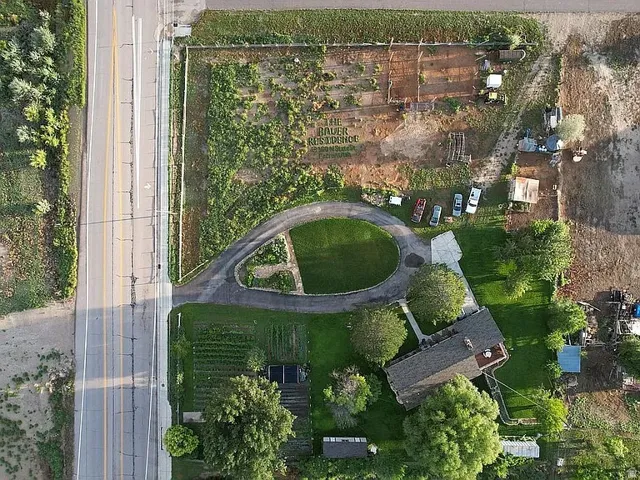 Extensive property featuring a circular drive, mature trees, manicured lawn, and planted garden areas