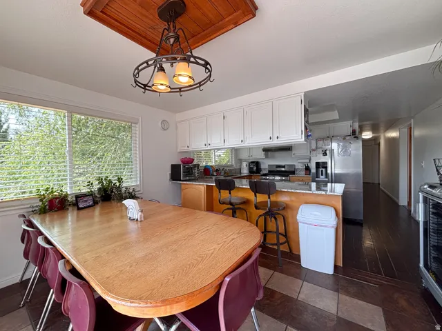Dining area featuring a large window, a wood-finish dining table, and direct access to the kitchen
