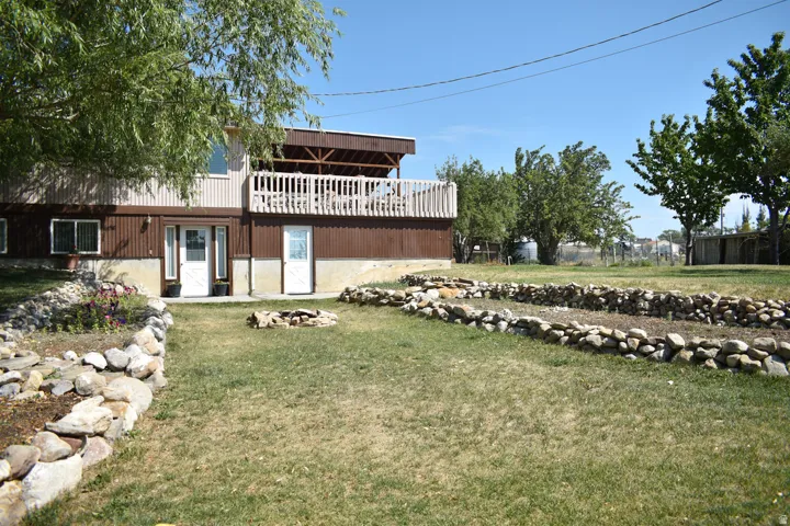 Two-story property featuring a lower-level entry, an upper-level covered deck with white railing, and a ground-level patio