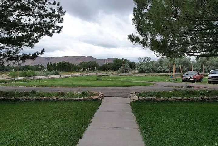 Expansive green lawn with a concrete pathway and stone-lined garden bed