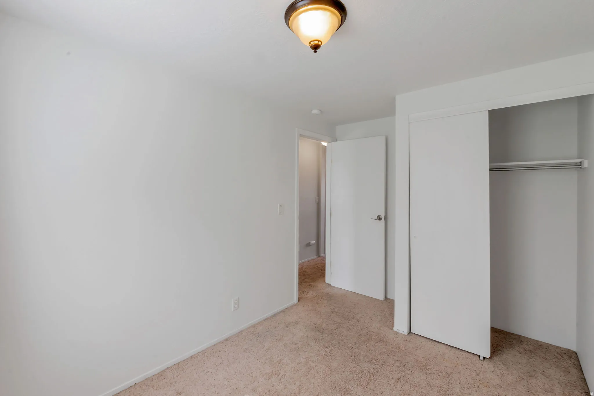 Carpeted room featuring a ceiling-mounted light fixture, white walls, and white trim