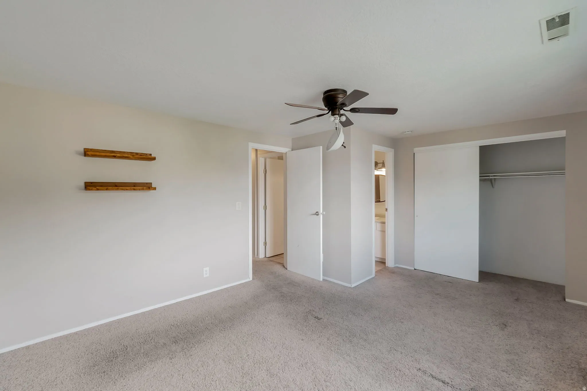 Carpeted room featuring a ceiling fan, sliding closet doors, and light-toned wall finishes