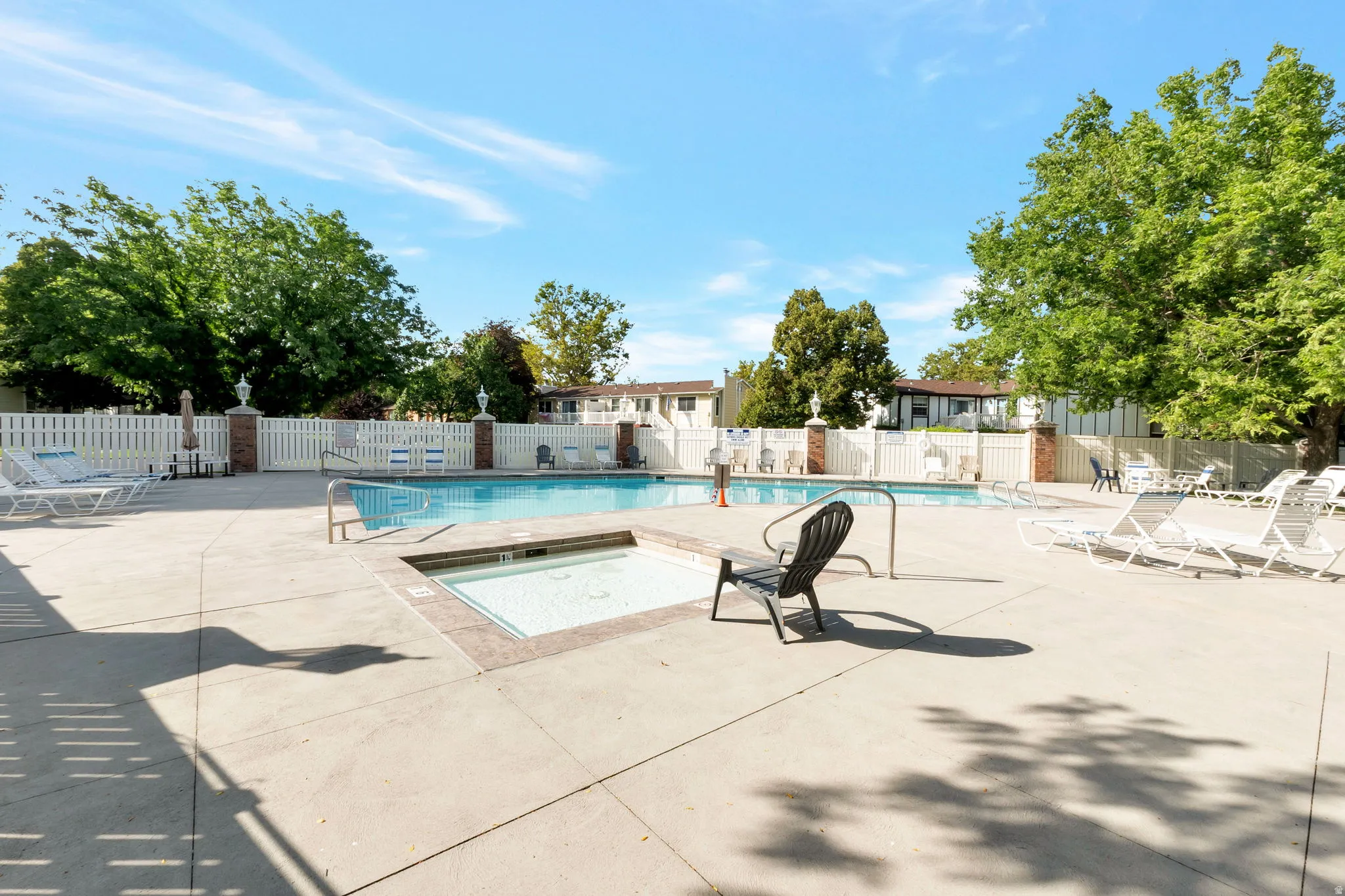 Outdoor pool area featuring a rectangular swimming pool, an integrated spa, and an expansive concrete deck