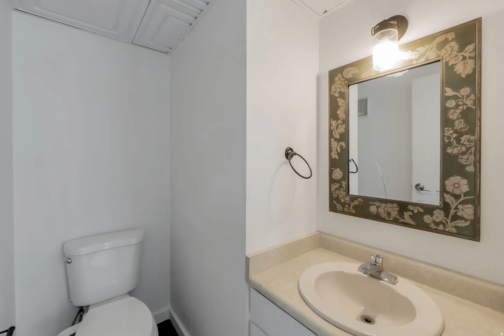 Bathroom vanity featuring a decorative framed mirror and a single-basin sink with chrome fixtures