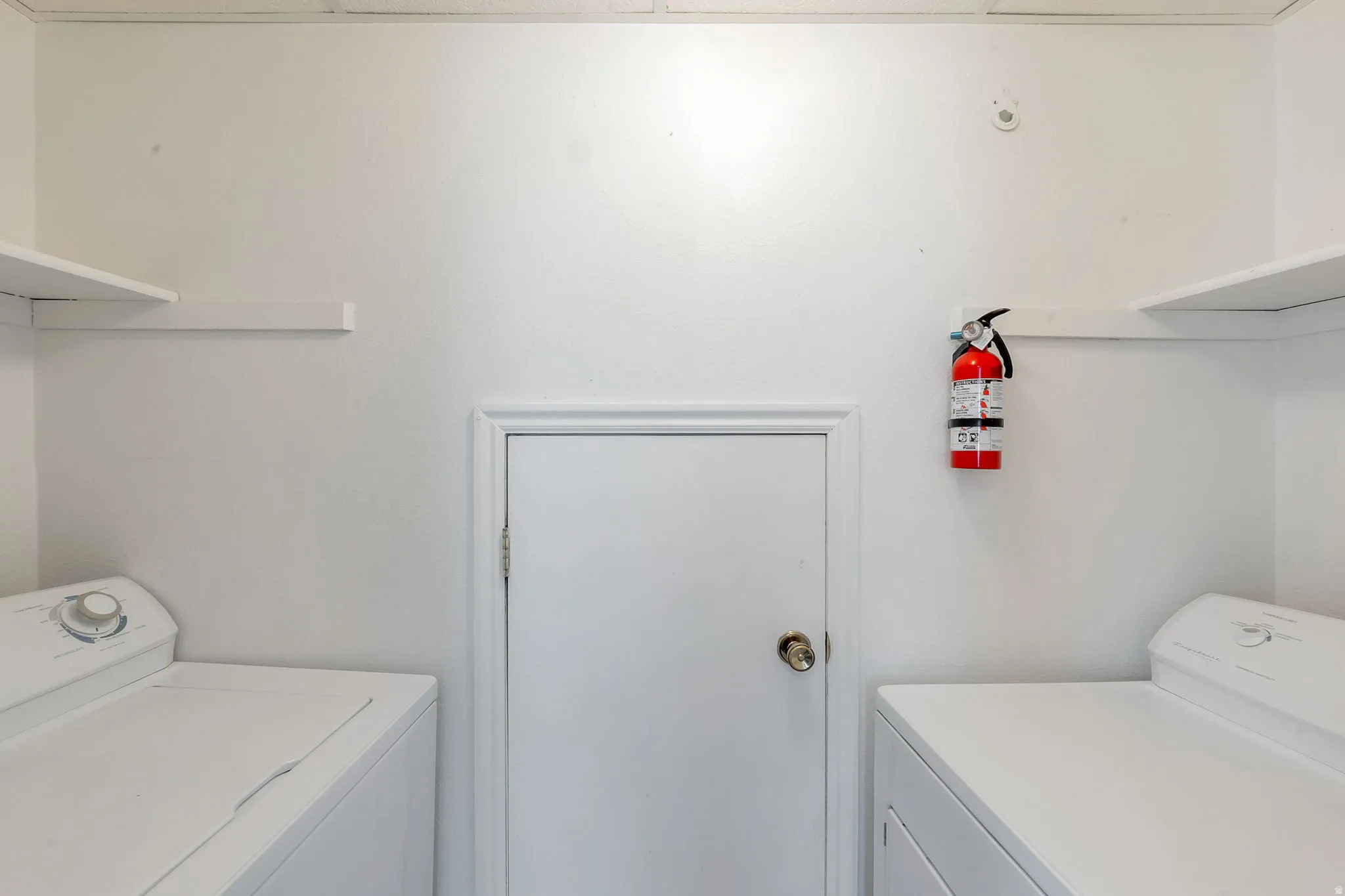 White walls with a central white door and two wall-mounted shelves