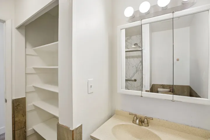 Bathroom vanity with a light-toned countertop, integrated sink, and dual-handle faucet