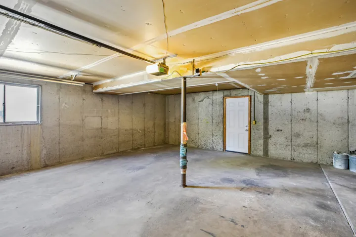 Unfinished basement with concrete flooring, exposed concrete walls, and a visible support column