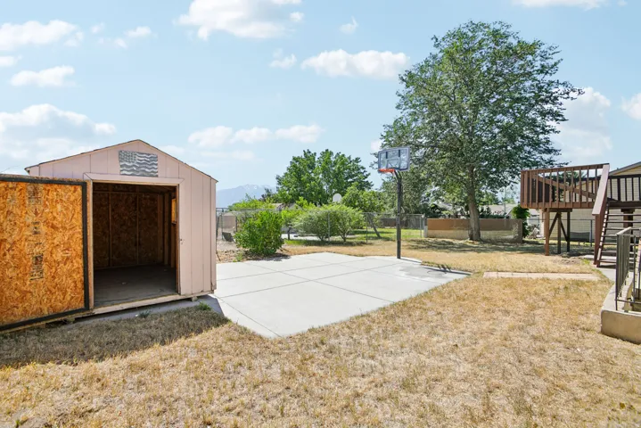 Expansive backyard featuring a concrete pad, a freestanding storage shed with an open doorway, and a multi-level deck with stairs