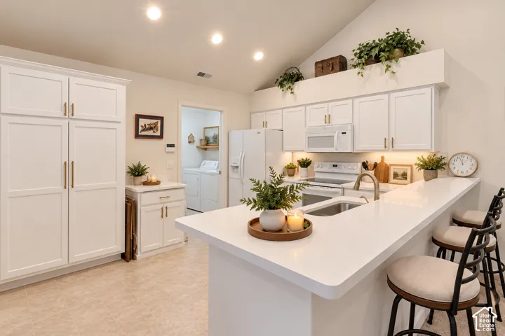 Kitchen featuring white cabinetry, stainless steel sink, recessed lighting, and a breakfast bar with solid surface countertops
