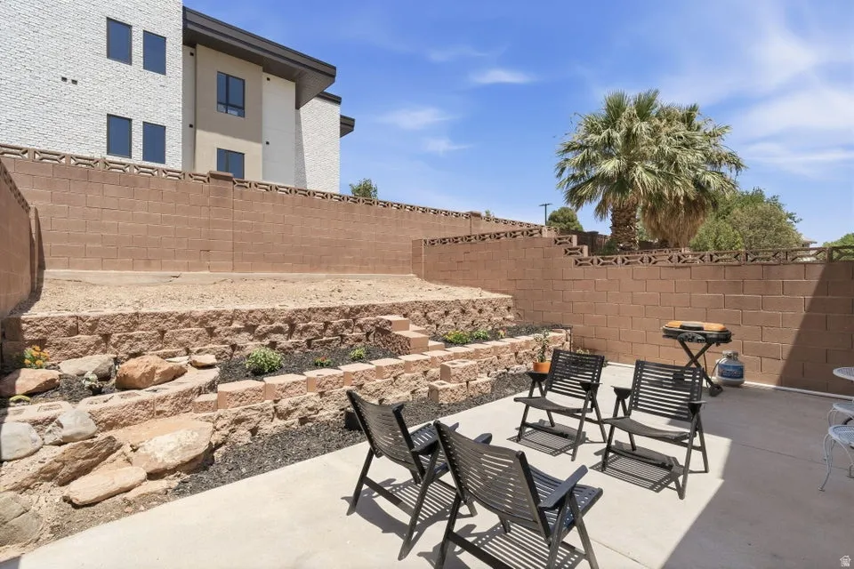 Concrete patio area featuring tiered landscaping with rock and planting beds