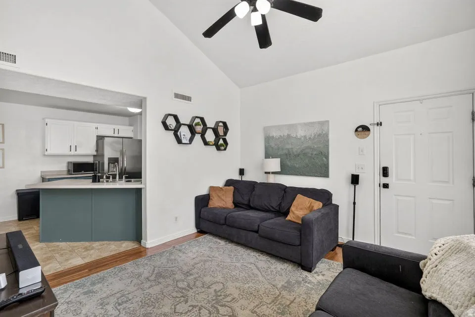 Vaulted ceilings enhance this living space featuring wood-finish flooring and a ceiling fan with integrated lighting
