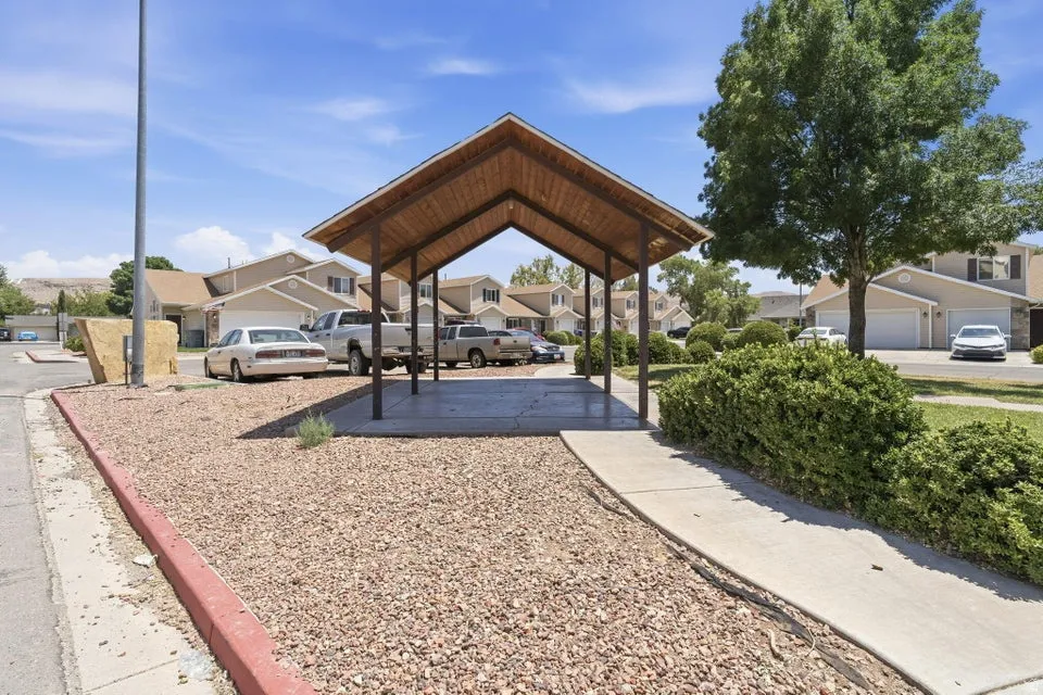 Covered parking structure with a peaked, wood-finish roof and concrete slab
