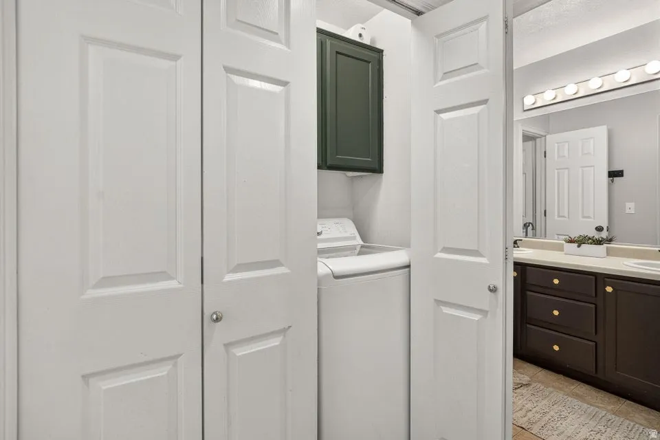 Laundry area with bifold doors, an overhead dark green cabinet, and a visible washer unit