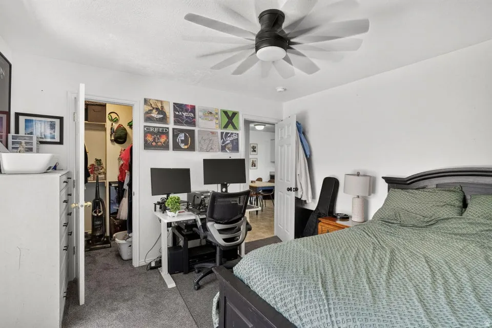 Carpeted bedroom featuring a ceiling fan, white walls, and a closet with a bifold door