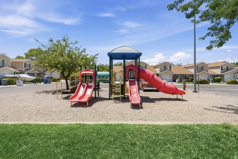 Community playground featuring multiple slides and climbing structures over a pea gravel surface