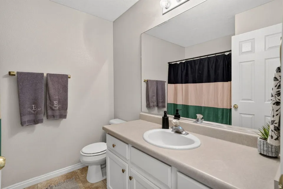 Bathroom featuring a white vanity with integrated sink, a large wall-mounted mirror, and a toilet